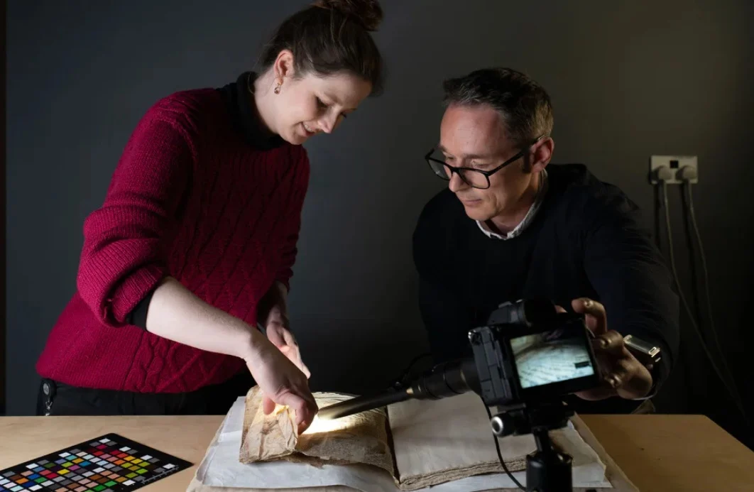 Консерваторът Сали Килби и Блажей Микула правят снимки на средновековния ръкопис.