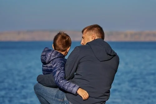 taming aggression father sits with son at shore by artem voropai shutterstock 1337898233 min